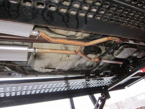 1991 Ford LTD Crown Victoria - The underside of a vehicle reveals a dual exhaust system with mufflers and piping.