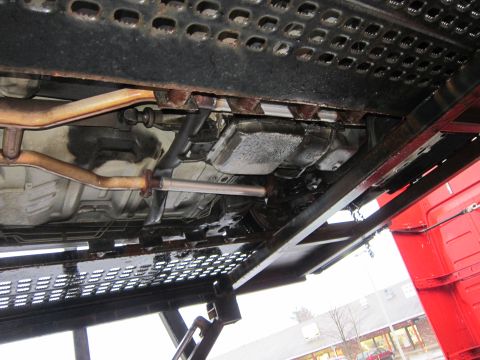 1991 Ford LTD Crown Victoria - Undercarriage view showing exhaust system and transmission parts on a car carrier.