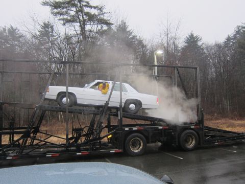 1991 Ford LTD Crown Victoria - White 1991 Ford Crown Victoria LTD loaded onto a car carrier with a driver inside.