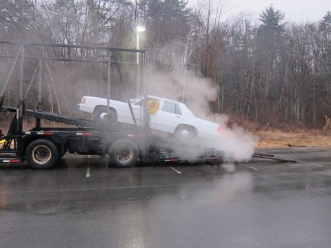 1991 Ford LTD Crown Victoria - A white sedan is being loaded onto a car hauler, with steam coming from the vehicle.