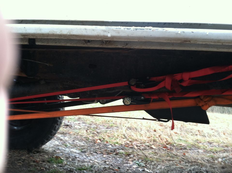 Underside of vehicle with red and orange straps securing it