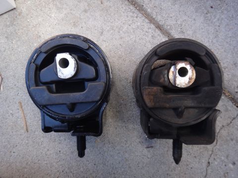 2003 Ford Taurus - Comparison of a new engine mount next to a used one, likely for a vehicle part replacement.