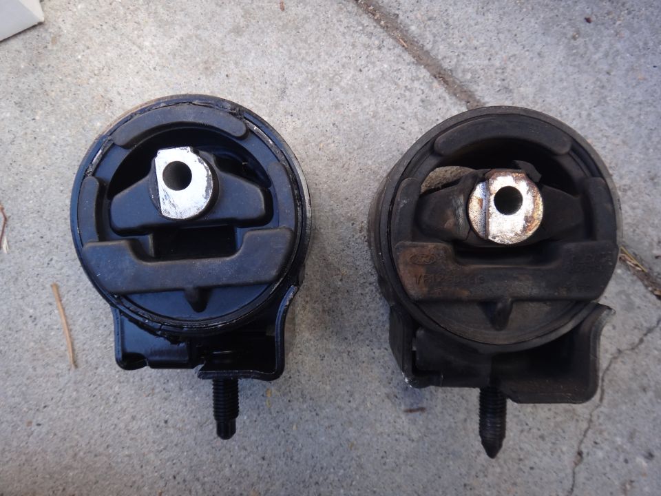 Two engine mounts, one new and one used, on a concrete surface