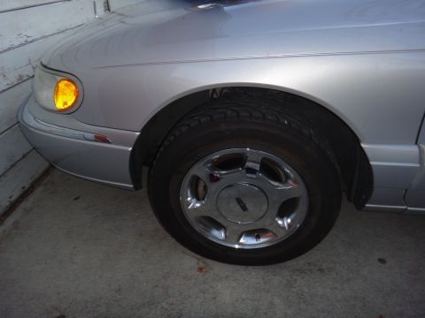 2000 Lincoln Continental - Close-up of a silver sedan's front passenger side, showing the wheel and fender detail.