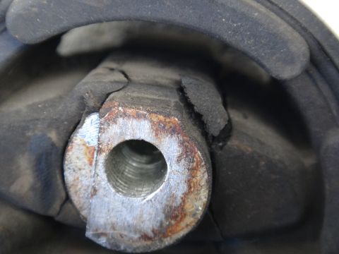 2003 Ford Taurus - This engine mount shows significant wear and tear, with the rubber component appearing to be torn and the metal parts showing rust.