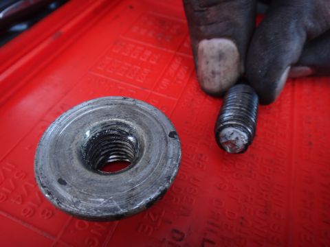 2003 Ford Taurus - Used motor mount bolt and nut shown on a red tray, likely for a Ford Taurus.