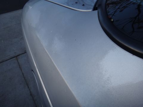 2000 Lincoln Continental - A close-up view of the side of a silver car, showing the fender and part of the rear window trim.