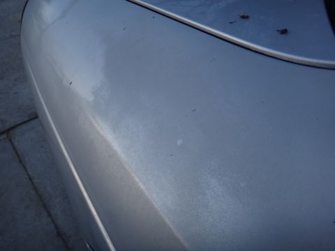 2000 Lincoln Continental - Close-up view of a silver car's fender, showing the texture and condition of the paintwork.