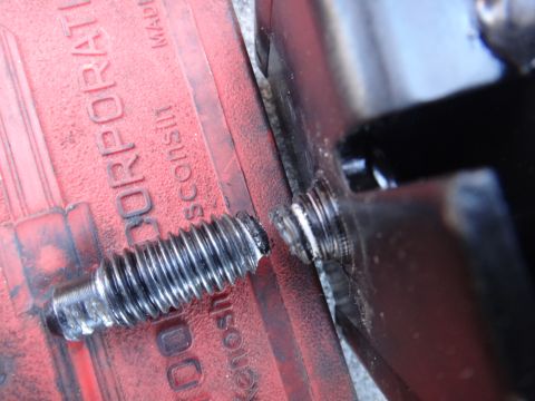 2003 Ford Taurus - Close-up of a damaged motor mount bolt on a red bracket, which has embossed text indicating it is from a corporation in Wisconsin.