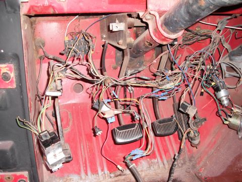1968 Ford Bronco - A complex wiring harness and brake and clutch pedals are visible in the red interior of this vehicle.