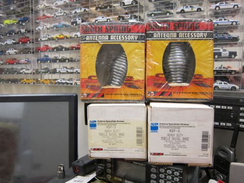 1991 Ford LTD Crown Victoria - Boxes of antenna accessories and radio equipment are displayed in front of a collection of model cars.