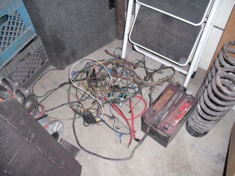 1968 Ford Bronco - A messy automotive wiring harness and battery are on the floor, possibly for a custom dash project.