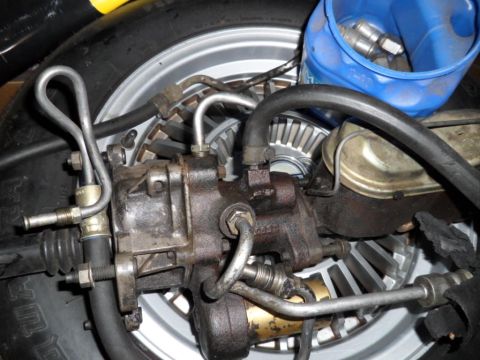 1973 Ford Ranchero - Power steering gearbox and brake master cylinder assembly with associated hoses and a tire in the background.