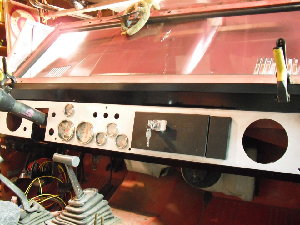 1968 Ford Bronco dashboard with multiple gauges, a key in the ignition, and exposed wiring