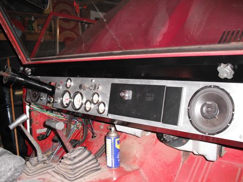 1968 Ford Bronco - Interior of a red project truck showing a custom brushed-aluminum dash panel with a cluster of white-faced aftermarket gauges, toggle switc…