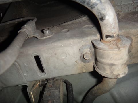 2000 Lincoln Continental - Underside view of a suspension sway bar bushing and its mounting hardware.