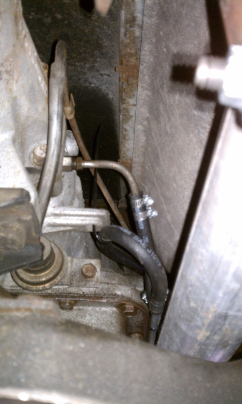 Close-up of a hose and metal lines under a vehicle, possibly part of the drivetrain or fuel system
