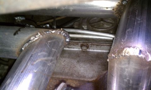 1979 Ford Bronco - Close-up of custom exhaust pipes and undercarriage components, showing welded joints and metal surfaces.