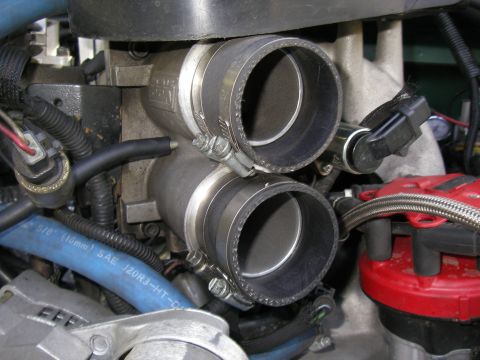 1990 Ford Bronco - Close-up of an engine's intake manifold dual throttle bodies and a blue hose.