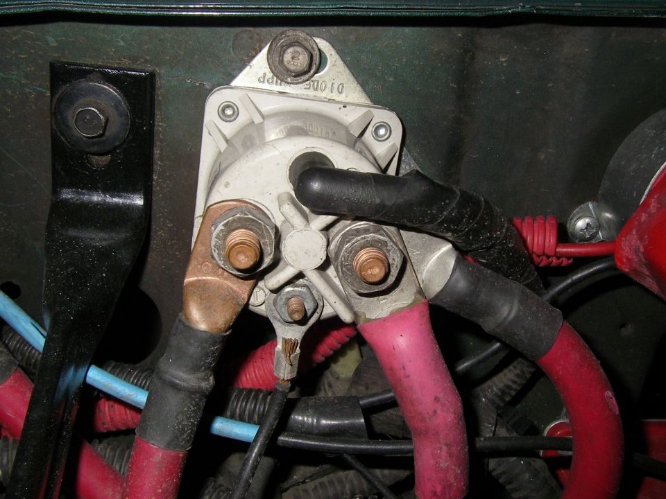 Starter solenoid with red and black battery cables connected. Some wiring is visible