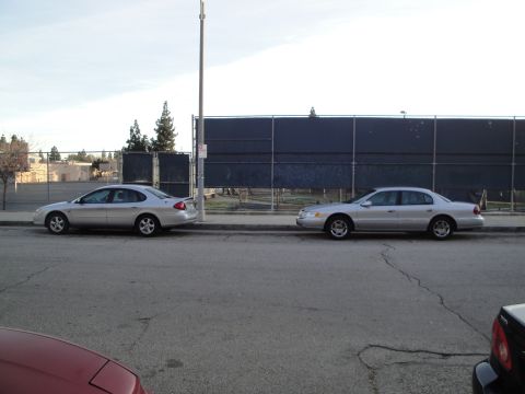 2000 Lincoln Continental - A silver 2000 Lincoln Continental is parked on the street next to another car.