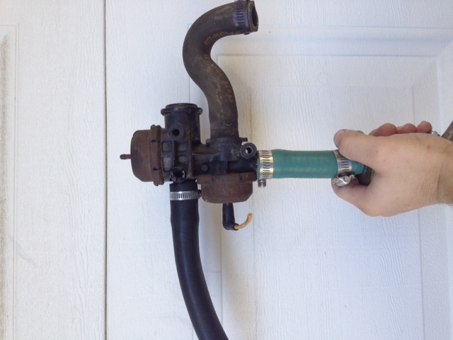 Rusty diverter valve with black and green hoses attached, held by a hand