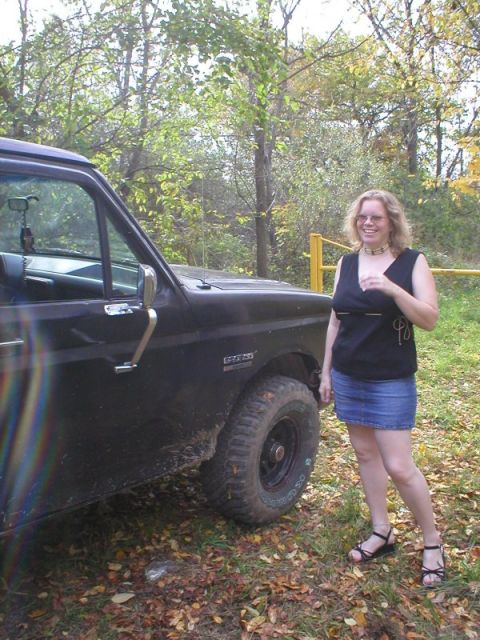 1989 Ford Bronco - Driver's-side view of a dark blue Ford truck on a grassy trail, showing the door with chrome handle, black mirror, a fender nameplate and a…