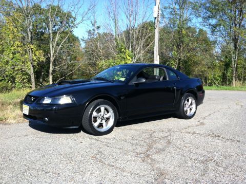 2002 Ford Mustang - This black 2002 Ford Mustang coupe is seen from a three-quarter front view, parked outdoors on a paved surface.
