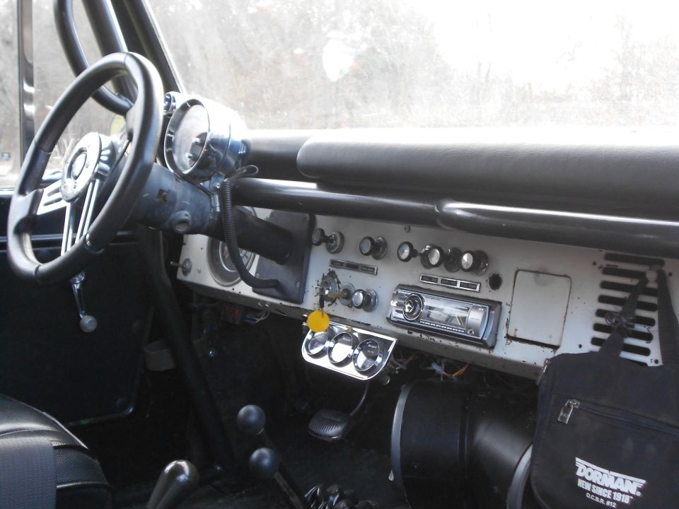 Vintage 4x4 interior dash with round gauges, toggle switches, and aftermarket stereo.