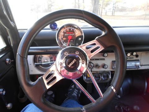 1967 Ford Mustang - Driver's-eye view of a vintage vehicle's white-painted metal dash through a chrome three-spoke Grant steering wheel with a black wrapped ri…