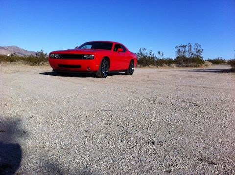 2010 Dodge Challenger - A red Dodge Challenger is parked on a gravel lot in a desert landscape.