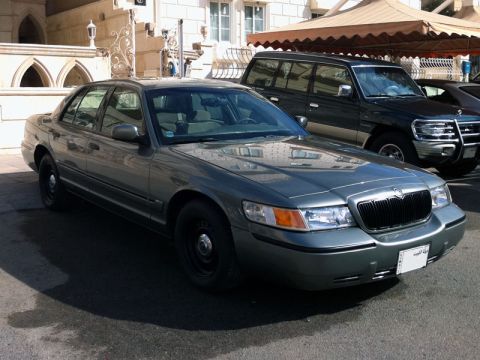 2001 Mercury Grand Marquis - A 2001 Mercury Grand Marquis is parked in front of a building, with another vehicle behind it.