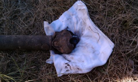 1979 Ford Bronco - A driveshaft component lies on a rag amidst dry grass.