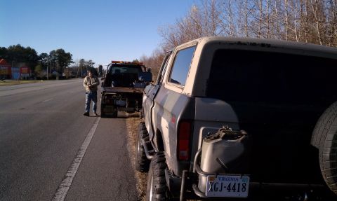 1979 Ford Bronco - A lifted 1978 Ford Bronco with a jerry can and spare tire is being towed by a tow truck on the side of a road.