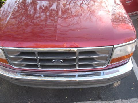 1995 Ford F-150 - Front view of a red 1995 Ford F-150, highlighting its chrome grille and headlights.