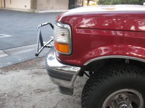 1995 Ford F-150 - The front corner of a red 1995 Ford F-150 pickup truck is shown, a chrome brush guard and bumper.