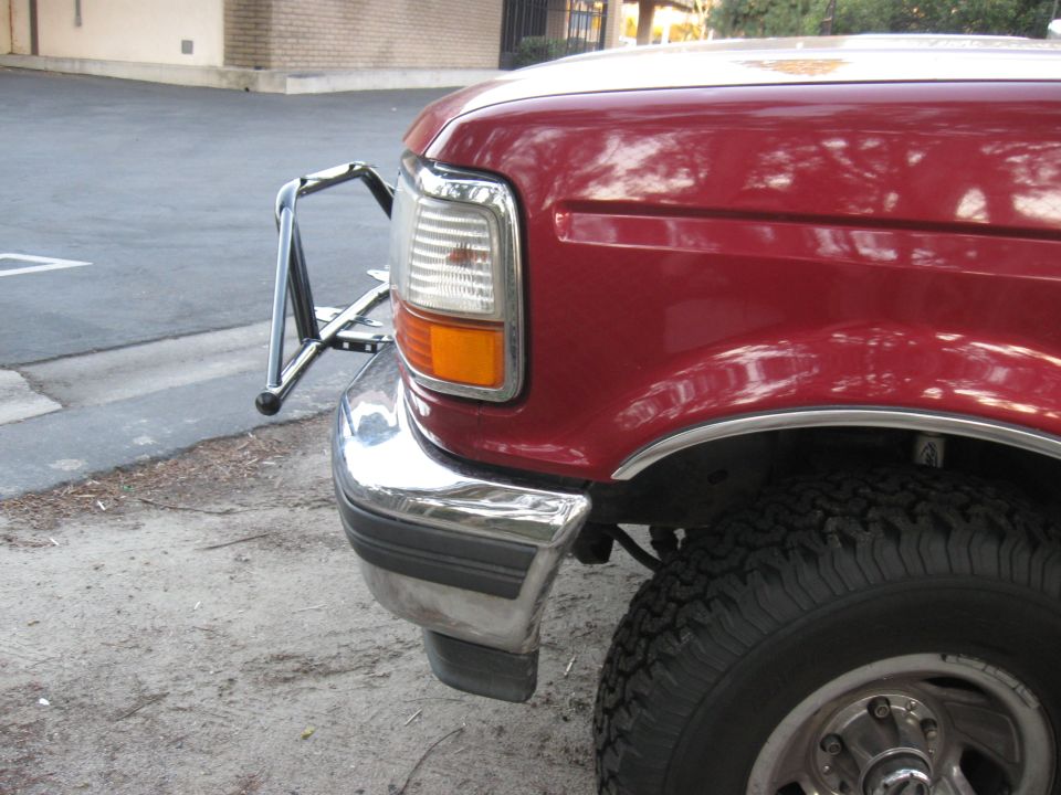 Front corner of a red 1995 Ford F-150 with a chrome brush guard and chrome bumper
