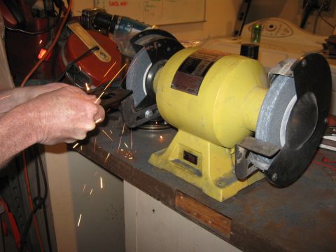 1995 Ford F-150 - A person is grinding a metal object on a yellow bench grinder, creating sparks.