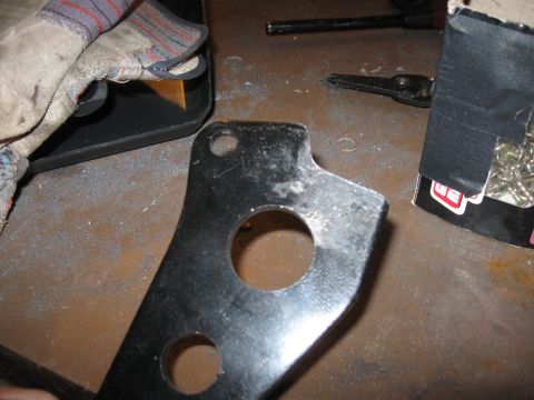 1995 Ford F-150 - A close-up view of a metal bracket with mounting holes, resting on a workbench surface.