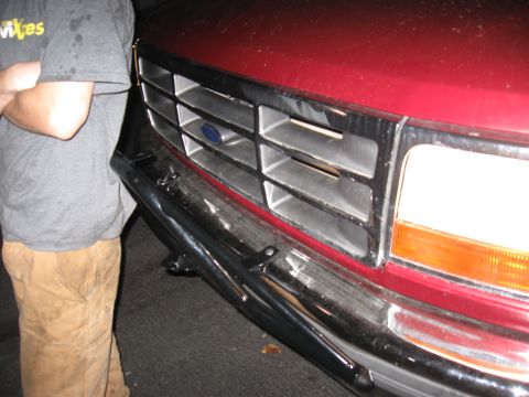 1995 Ford F-150 - Close-up of the front grille and bumper of a 1995 Ford F-150, with a person standing nearby.