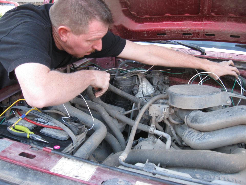 Man working on wiring in the engine bay of a 1995 Ford F-150