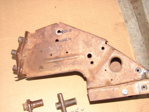 1973 Ford Ranchero - A heavily rusted metal component, possibly a bracket or frame piece, lies on a cardboard surface with two smaller metal pieces nearby.
