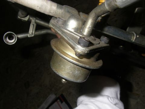 1990 Ford Bronco - A close-up view of a vehicle's fuel filter, showing its metallic components and mounting hardware.