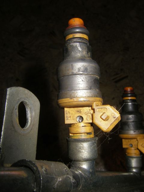 1990 Ford Bronco - Two fuel injectors are shown in close-up, one with visible part numbers and connectors.
