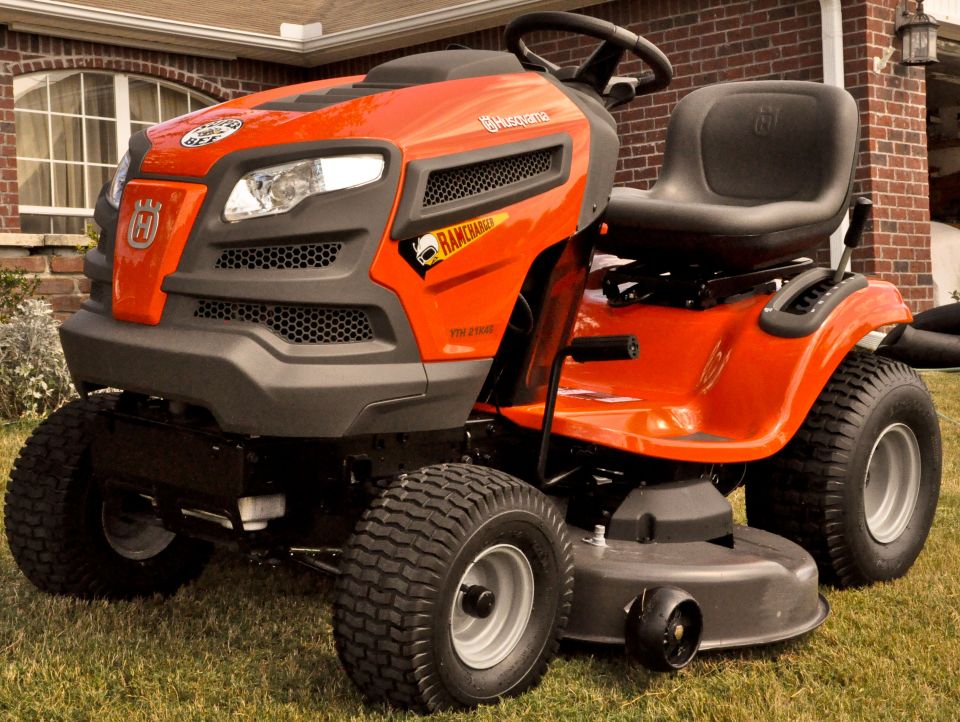 Orange Husqvarna riding lawn mower with black seat and steering wheel