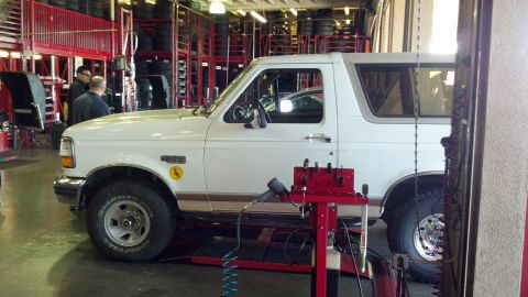 1996 Ford Bronco - A white 1996 Ford Bronco is shown in a service bay with equipment around it.