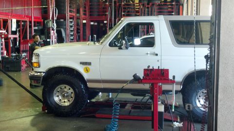1996 Ford Bronco - Side view of a white 1996 Ford Bronco being serviced on a lift.
