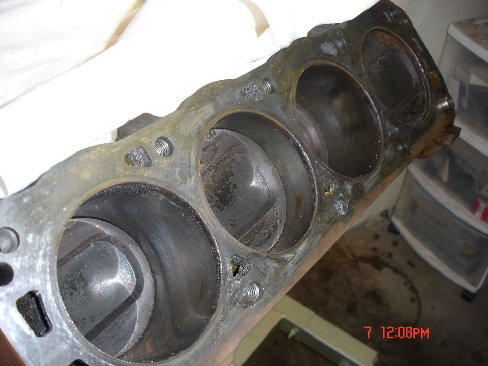 Engine cylinder block with pistons visible inside the cylinders. Some wear and tear is apparent on the block