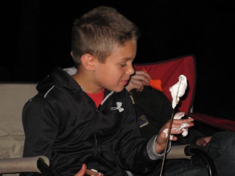 2008 Jeep Wrangler - A young boy enjoys roasting a marshmallow on a stick during a nighttime campfire.