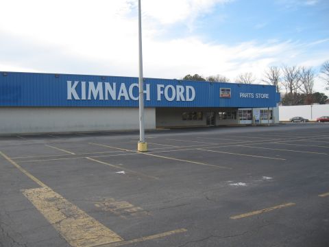 1968 Shelby GT500 - Exterior view of Kimnach Ford Parts Store on a partly cloudy day, with an empty asphalt parking lot in the foreground.